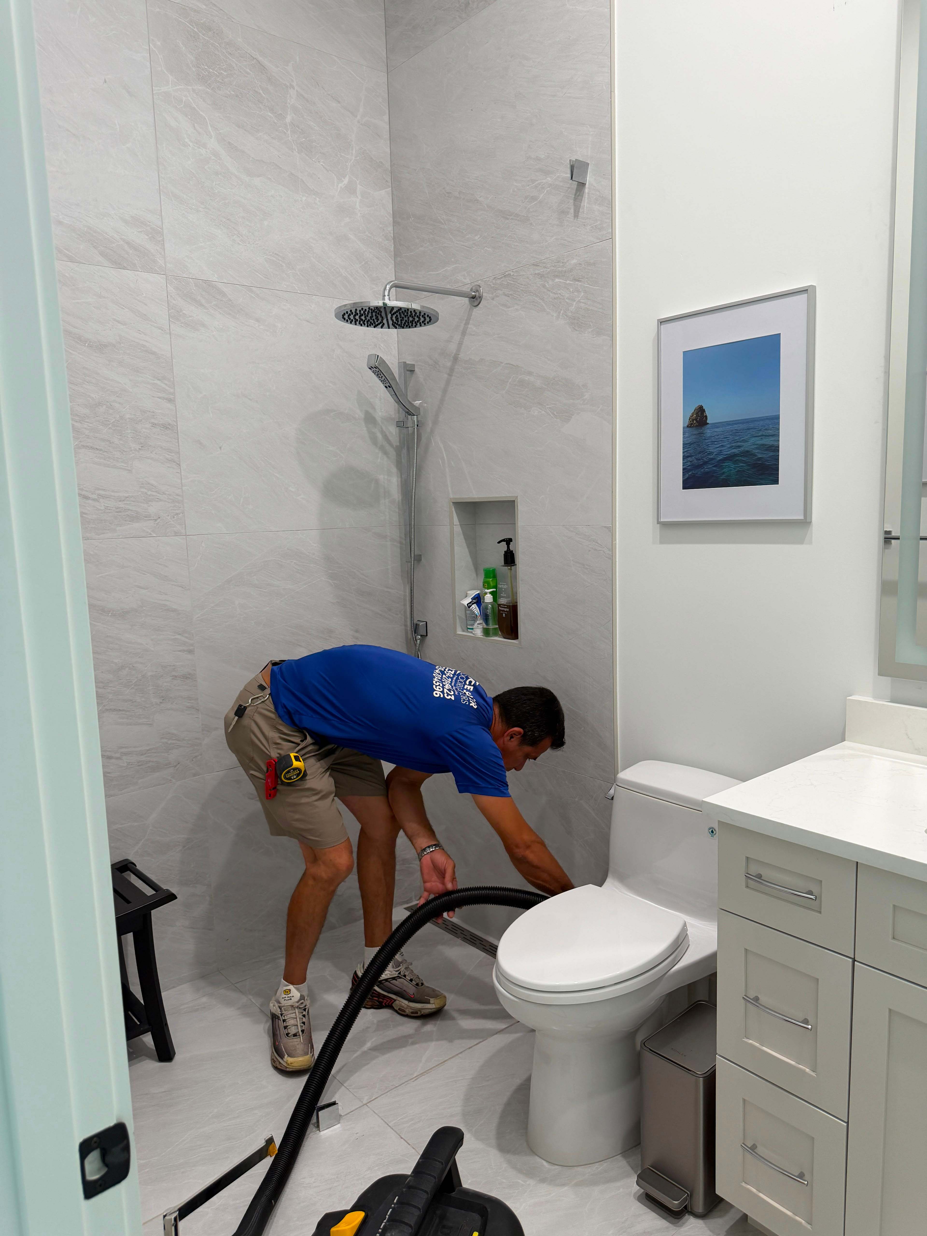 A BCE installer vacuuming the finished bathroom before leaving the job